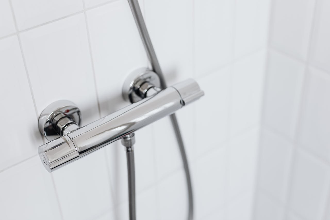 Modern chrome shower faucet on white tiled wall, elegant and clean design.